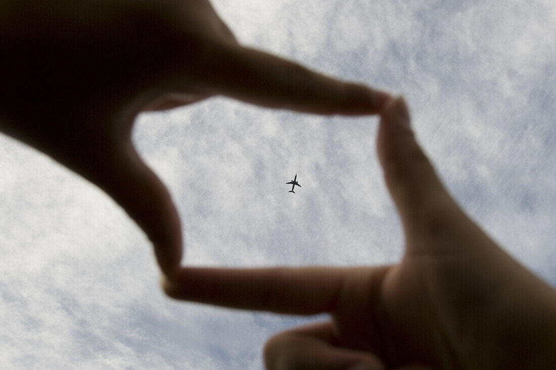 An airplane framed by 'cinema' fingers.