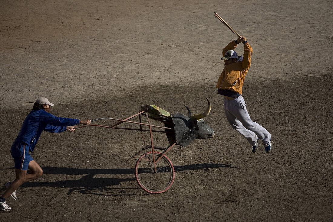 A bullfighter practices stabbing banderillas behind a stuffed bull's head mounted on a bicycle wheel pushed by another bullfighter in the ring in Apizaco, Tlaxcala, Mexico, October 1, 2008.