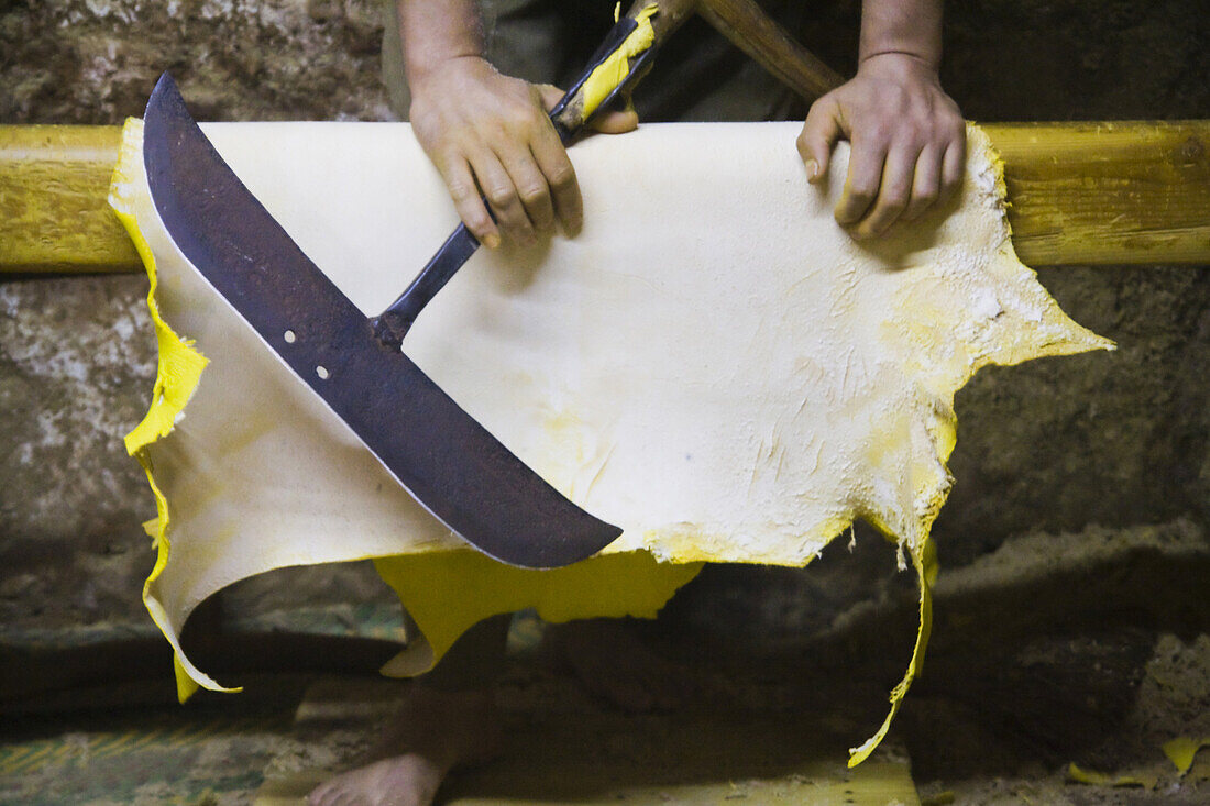 A worker holds the large blade which he uses to file down the rough side of yellow dyed sheep skins at the Berber leather tannery in Fes El-Bali, Morocco, on October 31, 2007.