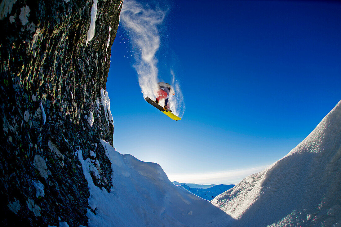 Snowboarder doing a back flip over rocks, Hochfuegen, Zillertal, Austria