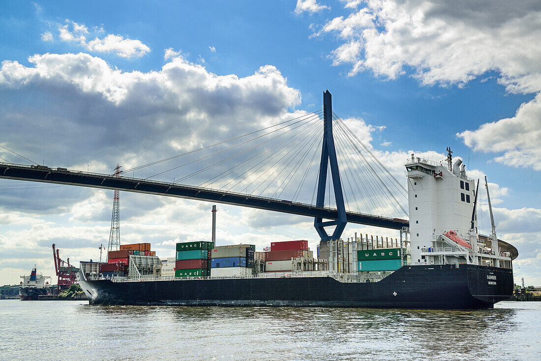 Container ship sailing on the river Elbe beneath the Koehlbrandbruecke bridge, river Elbe, Hamburg, Germany