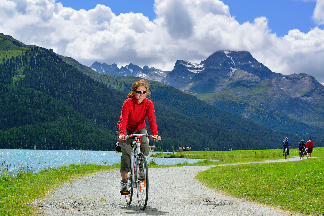 Woman cycling along Lake Silvaplana, Upper Engadin, Engadin, Canton of Graubuenden, Switzerland