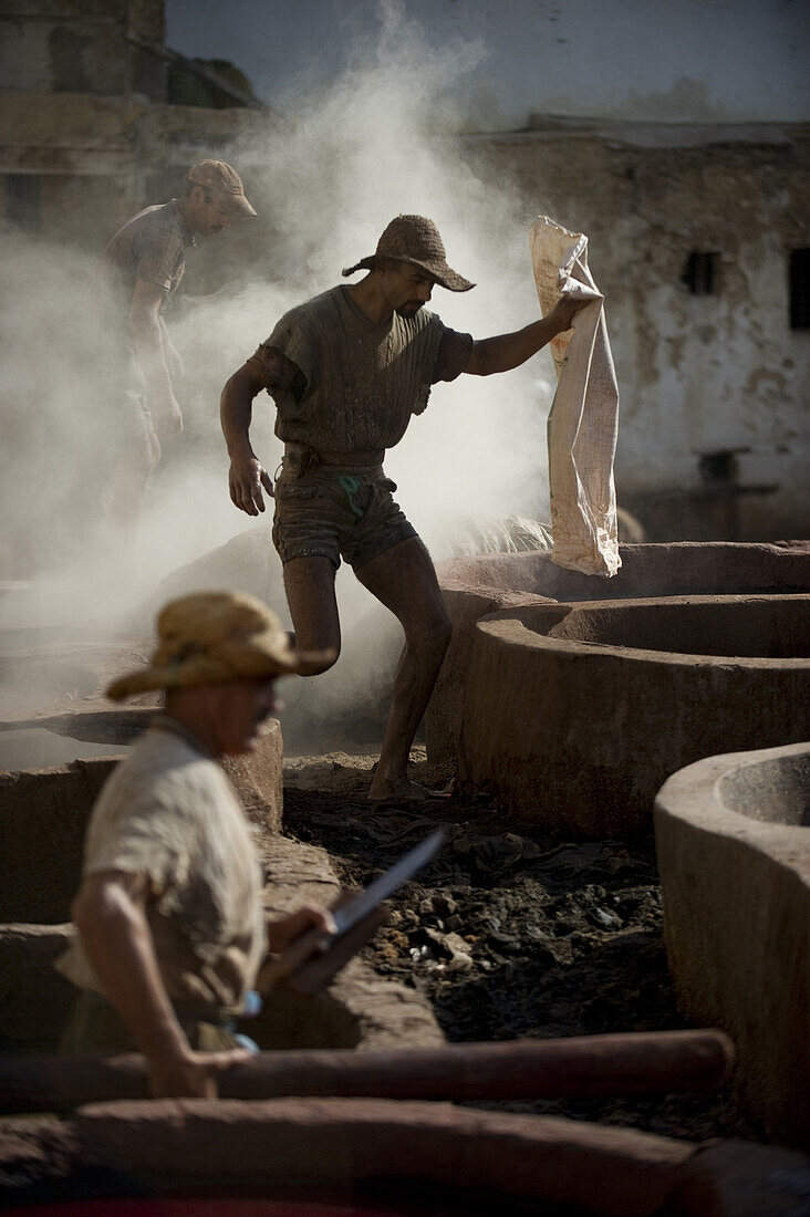 A man walks barefoot over the open pots of leather stains and dyes after pouring toxic dye powder into one of the empty vats at an ancient Moroccan tannery.