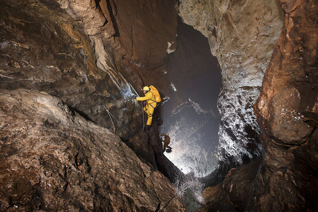 Two male British cave explorers rappel down the Grand Cascade deep underground in the main gallery of the classic famous cave in France called The Gouffre Berger high in the Vercors region.