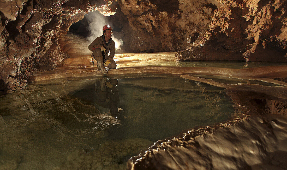 An American student caver admires these delicate gour pools deep underground in a cave called Teca in The Picos de Europa, Northern Spain.