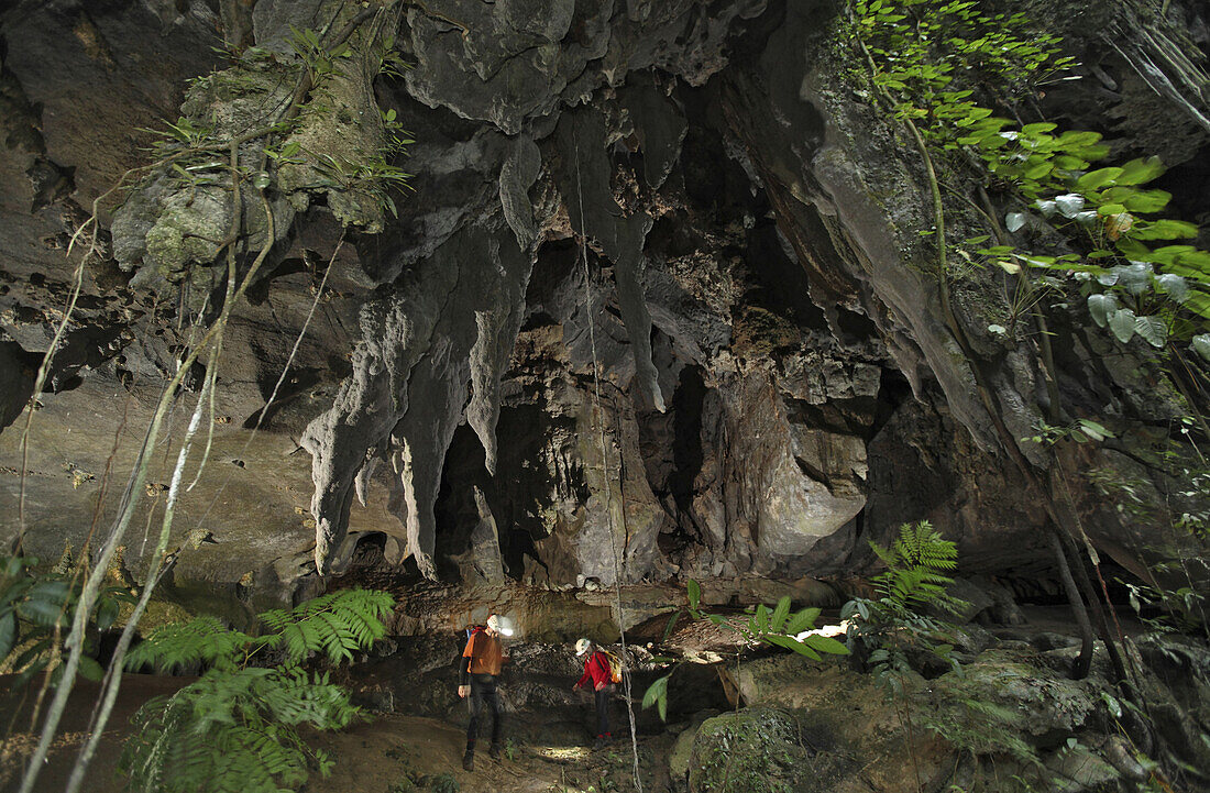 Cave explorers at the entrance to Racer Cave, deep in the rainforest of Mulu National Park, Sarawak, Borneo.