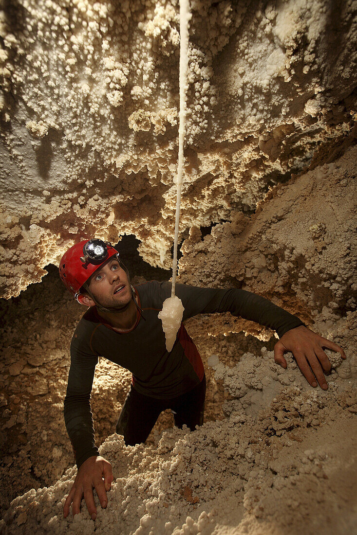 A young British cave explorer admires an unusual cave crystal formation clinging to the ceiling of this particular cave called Whiterock in Gunung Mulu National Park, Sarawak, Borneo.