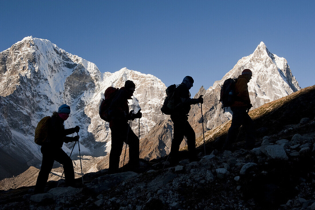 Hikers silhouetted against a sunrise mountain backdrop above Dhugla, 16,000ft.-trek to mt. everest base camp.