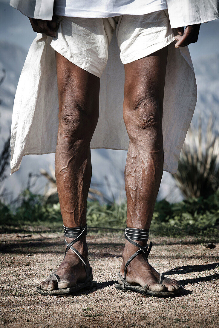 Legs of a tarahumara runner from Tatahuichi community with his traditional huaraches and clothes, at the Ultramaraton de los Canones in Chihuahua.