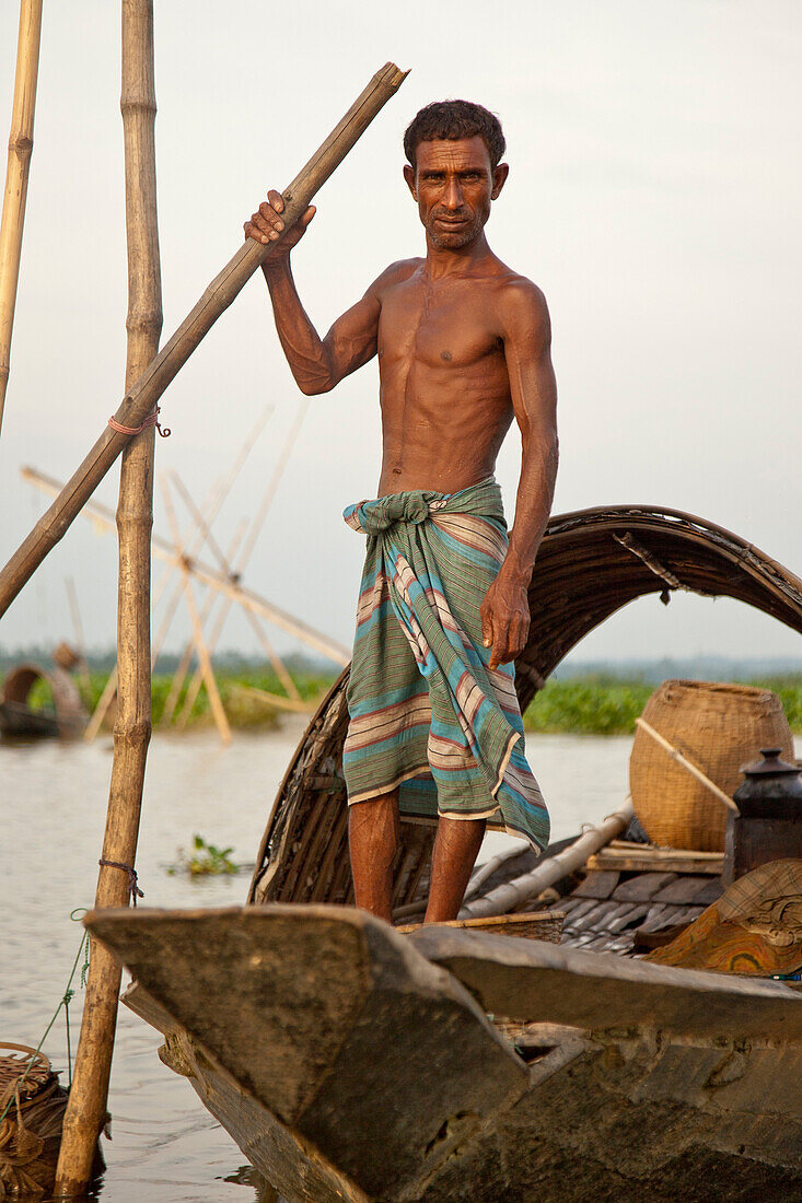 Srimangal,  Bangladesh - July 2011:  Bangladeshi man living and fishing on a small boat in a seasonally flooded area near Srimangal,  Bangladesh.