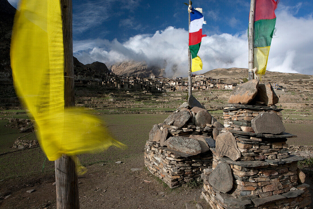 Naar village through Buddhist prayer flags. Houses in Naar village are closely built to save the arable land. Manang, Nepal.