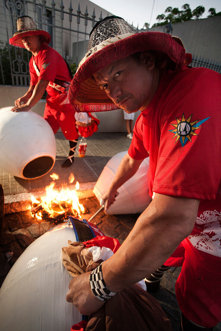'A couple of men heating the drums before playing at the ''desfile de llamadas'' during the carnival celebrations in Colonia del Sacramento, Uruguay.'