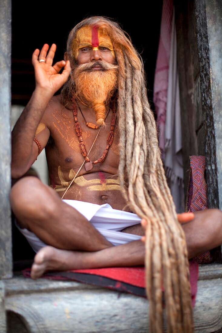 A Hindu priest, a sadhu and esthetic, with body paint poses in a Kathmandu, Nepal temple.