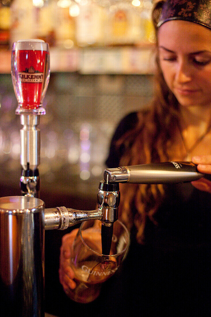 VANCOUVER, BRITISH COLUMBIA, CANADA. A woman pours a beer at a bar.