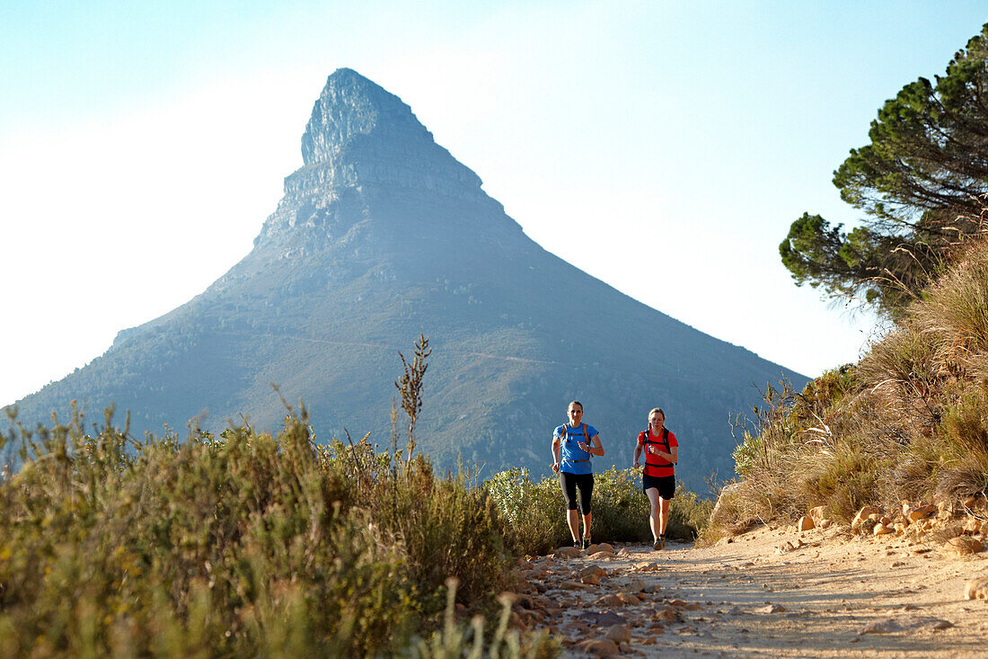 Katrin Schneider and Susann Scheller running on the Pipe Track above Camps Bay and below the Twelve Apostles. The peak in the back is Lion's Head. Cape Town, South Africa.