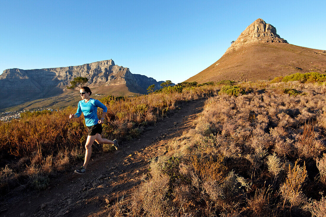 Susann Scheller running on the trail from Lion's Head to Signal Hill above the city of Cape Town just after sunrise. Cape Town, South Africa.
