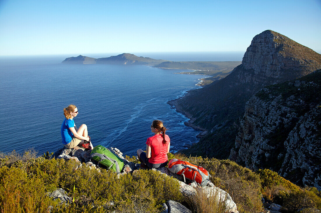 Katrin Schneider and Susann Scheller having a break while hiking on the Hoerikwaggo Trail from Cape Point to Table Mountain in Cape Town. In the background is famous Cape Point. South Africa.