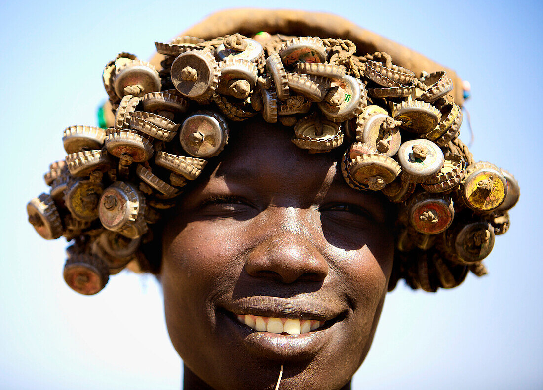 Woman from the Bumi tribe wearing hat made out of recycled bottle lids. Omerate,Omo Valley,Ethiopia,2010
