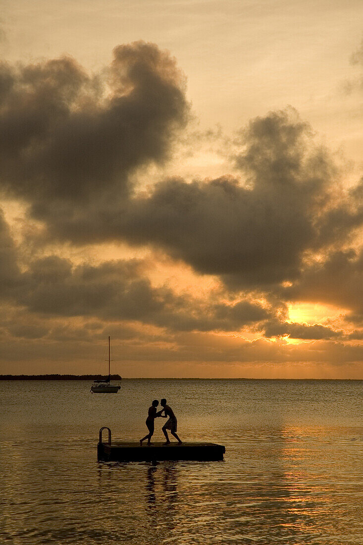 Girl and boy wrestling on dock, Ley Largo, Florida