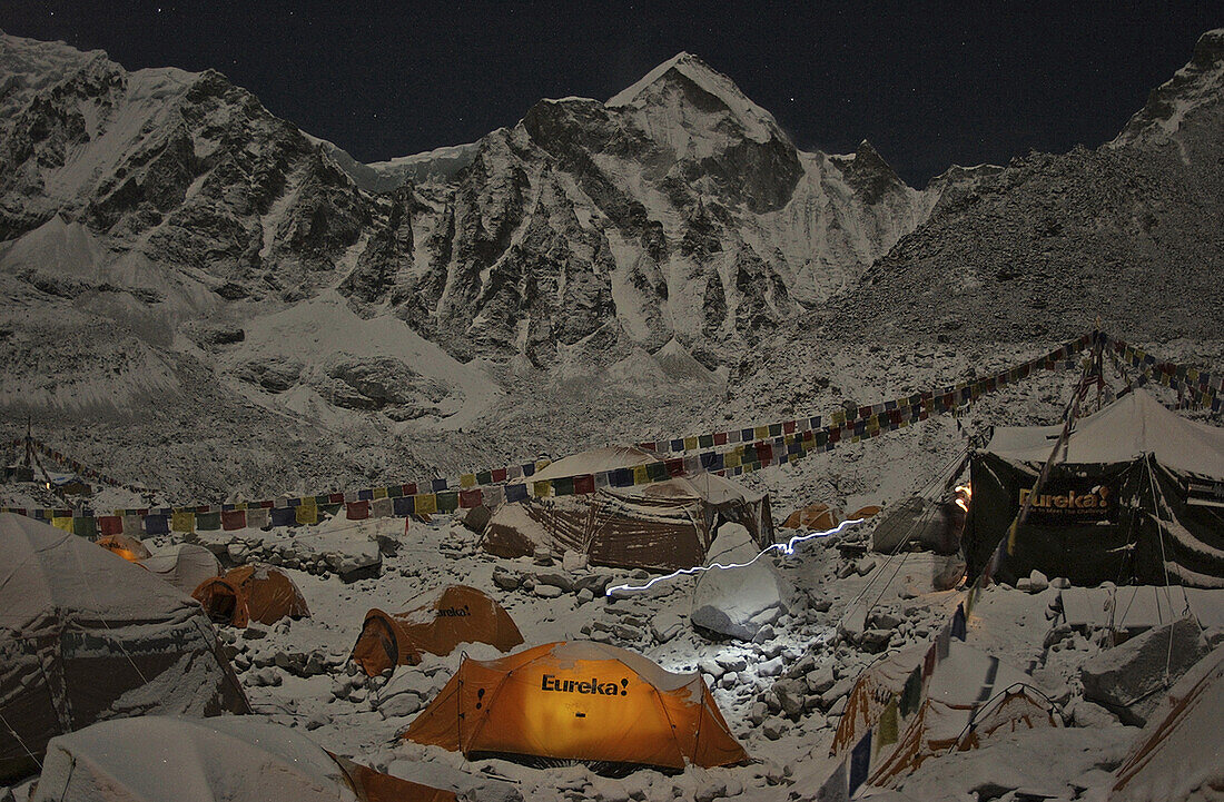 A climber's headlamp streaks through a night scene at Everest's Khumbu Basecamp, Nepal.