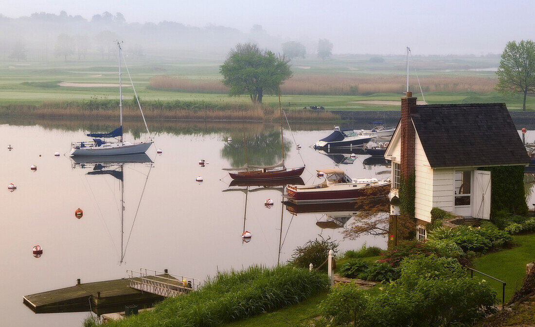 SOUTHPORT, CT - MAY 13: Pleasure boats sit a their glassy moorings in Southport Harbor. Morning fog settles across the harbor on the golf course of the Country Club of Fairfield. A number of the homes that line the harbor have private access to water.