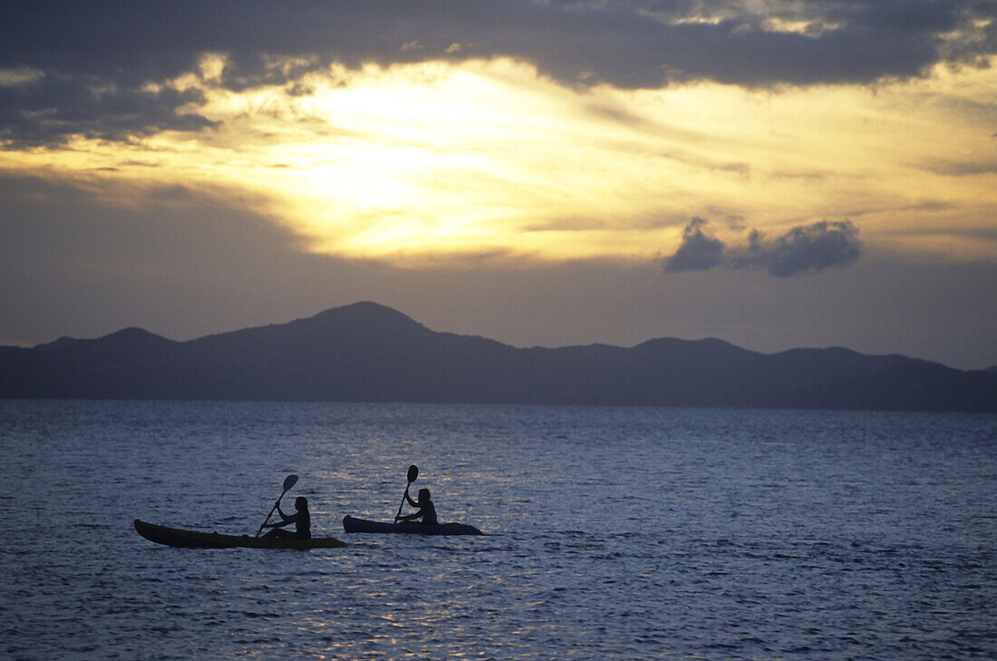 Sea Kayakers explore the Coron Islands at sunset, Palawan Islands, Phillippines. Photo by Greg Von Doersten/Aurora
