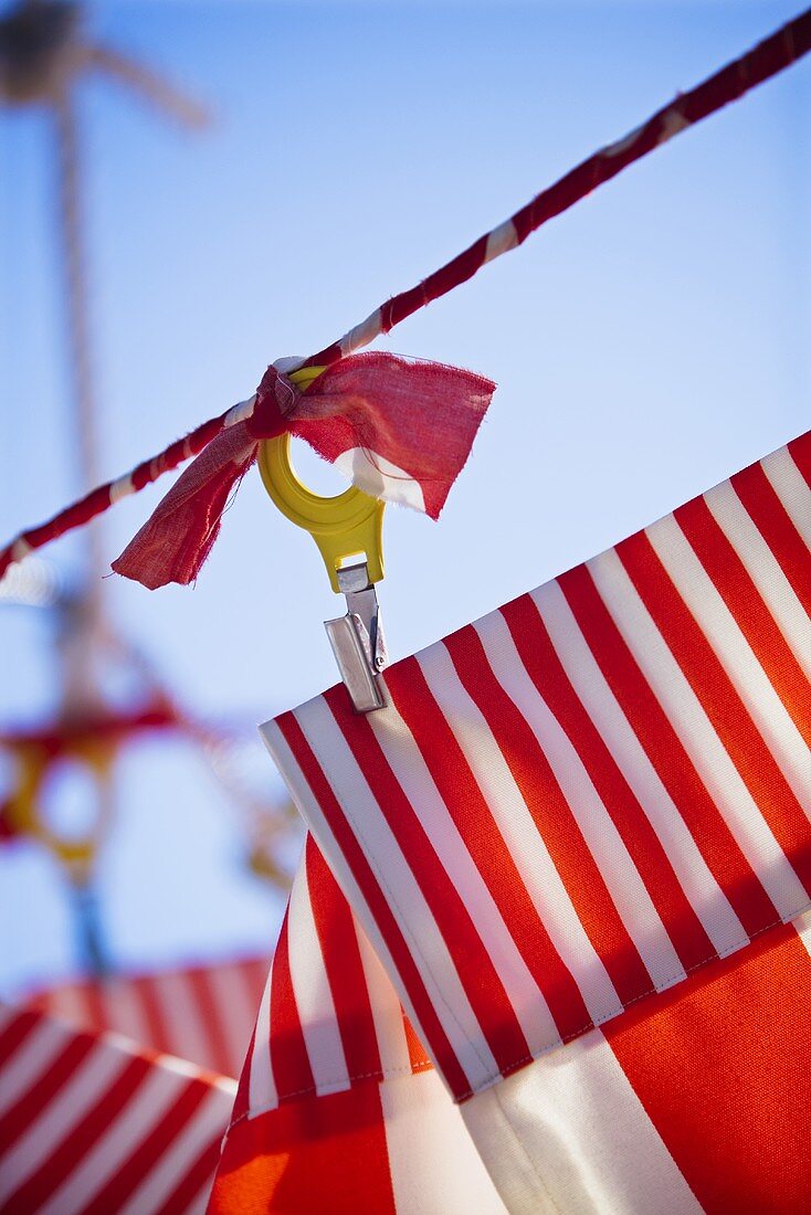 Red and white striped fabric attached to a rope with clips