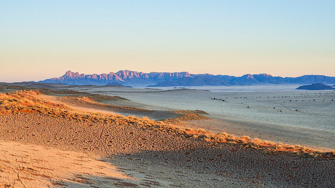 First light on the dunes and mountains of NamibRand, Namib Desert, Namibia, Africa