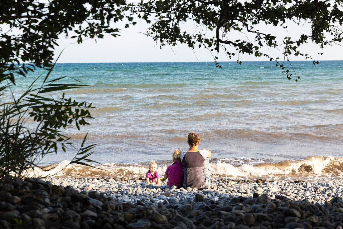 Mother and children (1-4 years) sitting at Baltic Sea beach, Klintholm, Mon island, Denmark