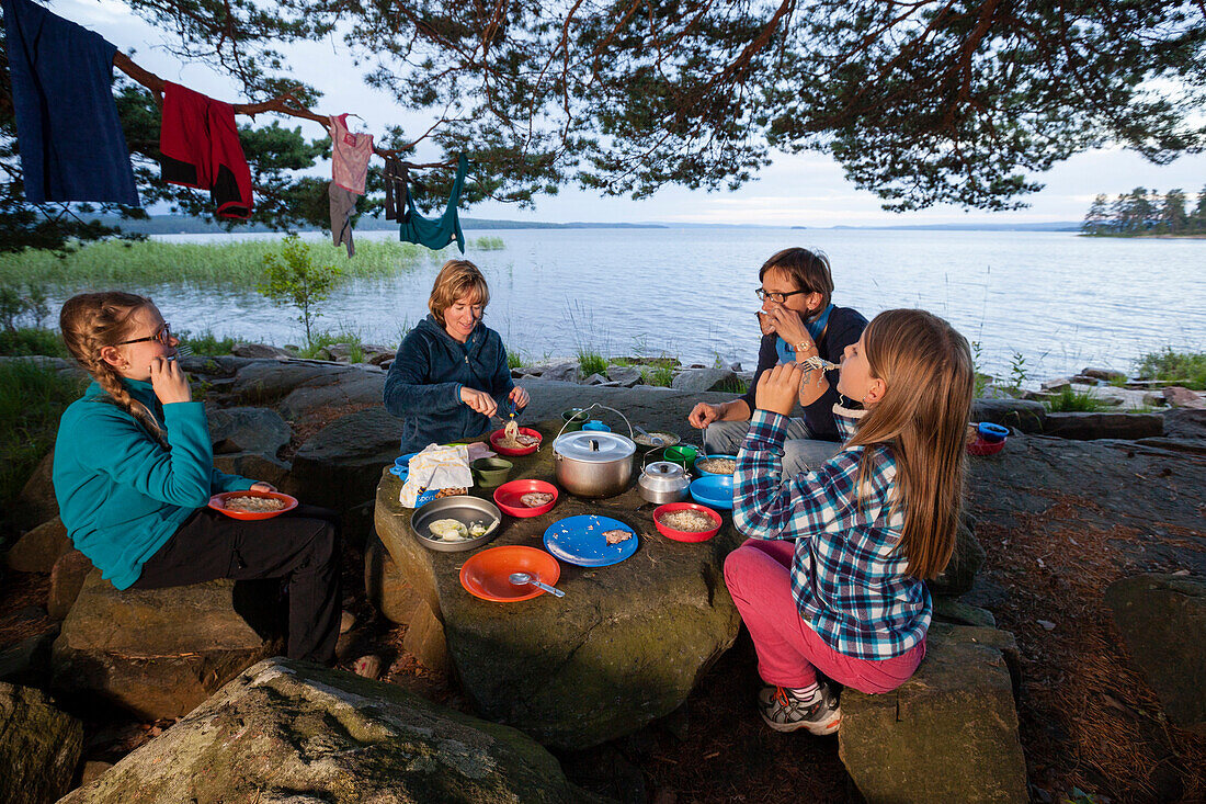 Zwei Mädchen und zwei Frauen beim Nachtessen am See Glafsfjorden, Värmland, Schweden