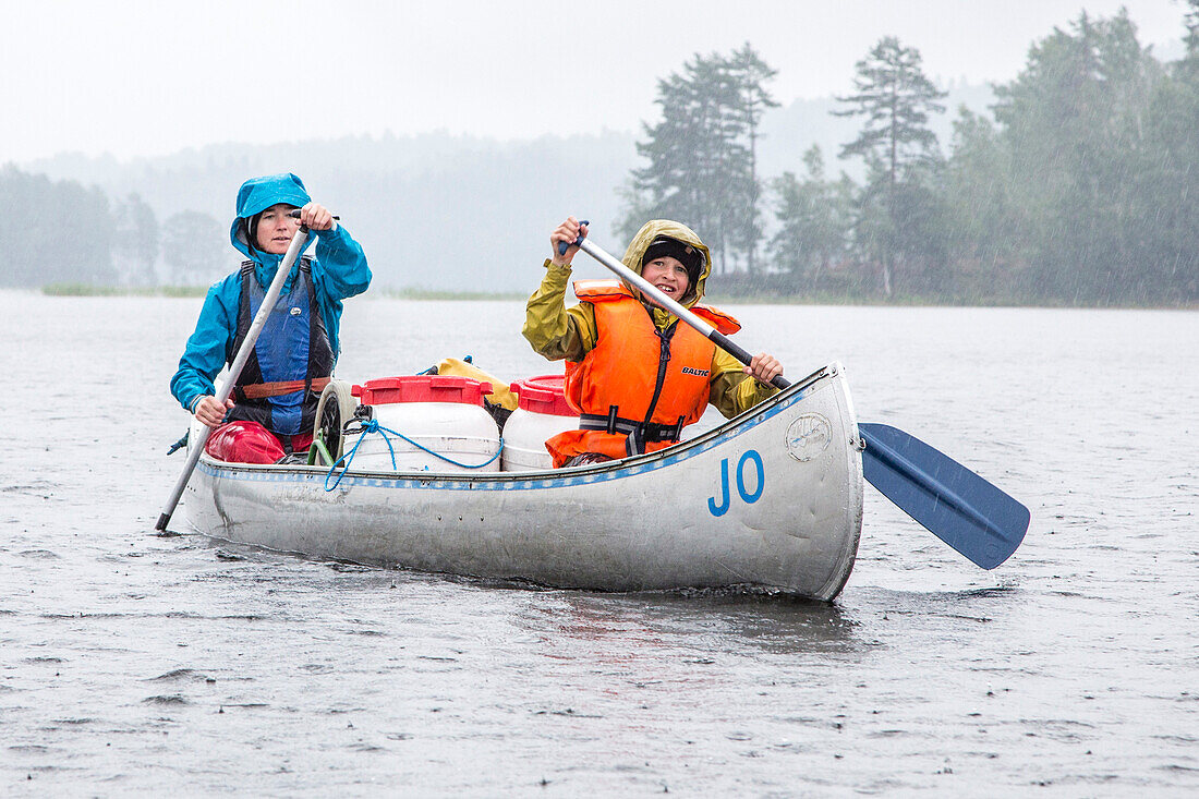 Eine Frau und ein Junge in einem Kanu im Regen auf dem Värmelnsee, Värmland, Schweden