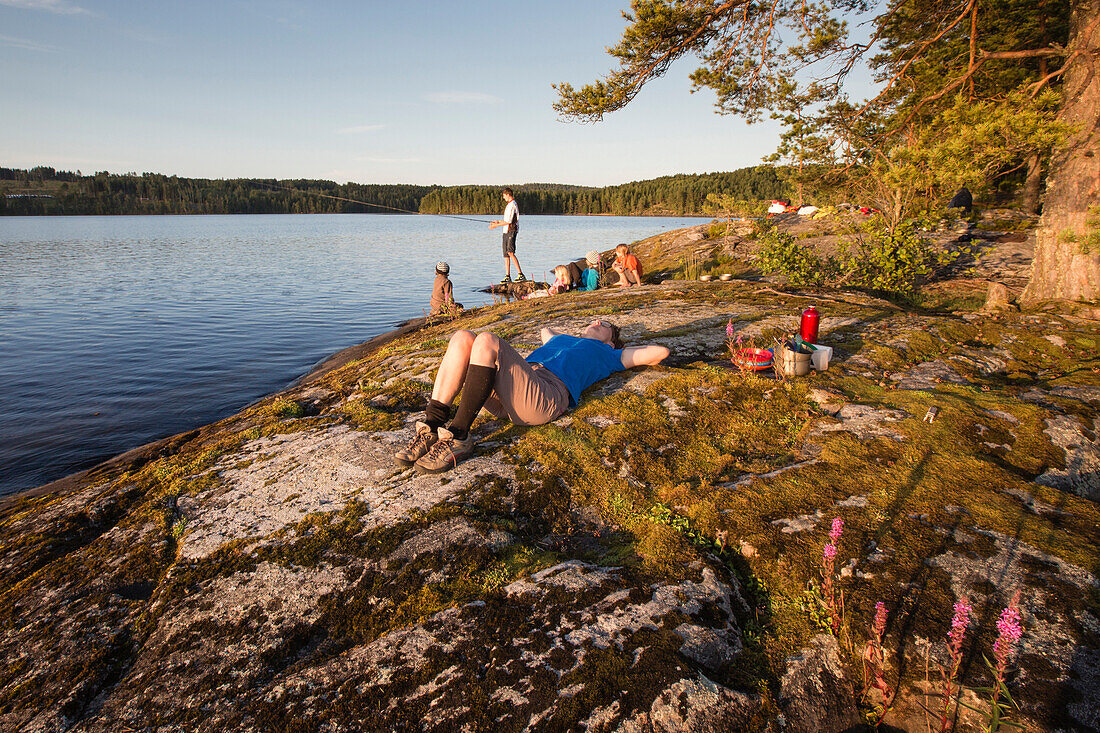 A group of people on the rocky shore of an island at Vaermeln Lake, Vaermland, Sweden