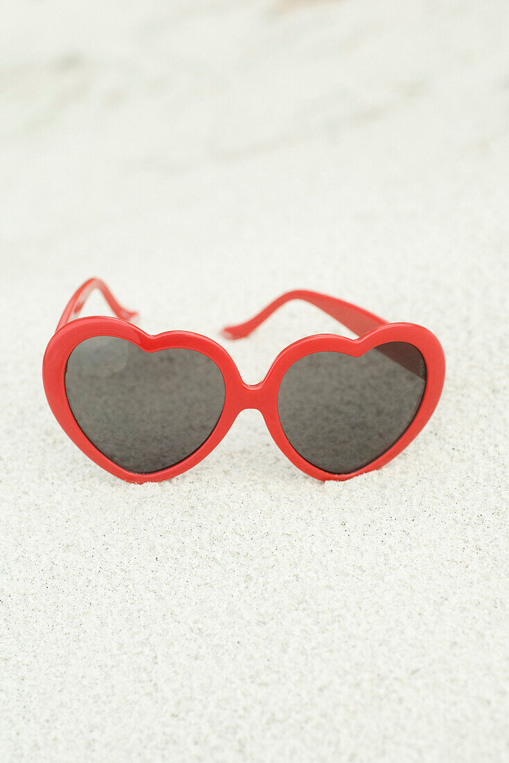 Heart-shaped sunglasses on beach