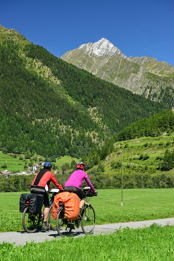Two cyclist passing Inn cycle route towards Piz Linard, Lavin, Lower Engadin, Canton of Graubuenden, Switzerland