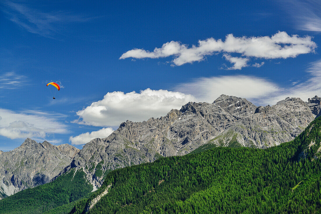 Paraglider in mid-air, Sesvenna Alps in background, Ardez, Lower Engadin, Canton of Graubuenden, Switzerland