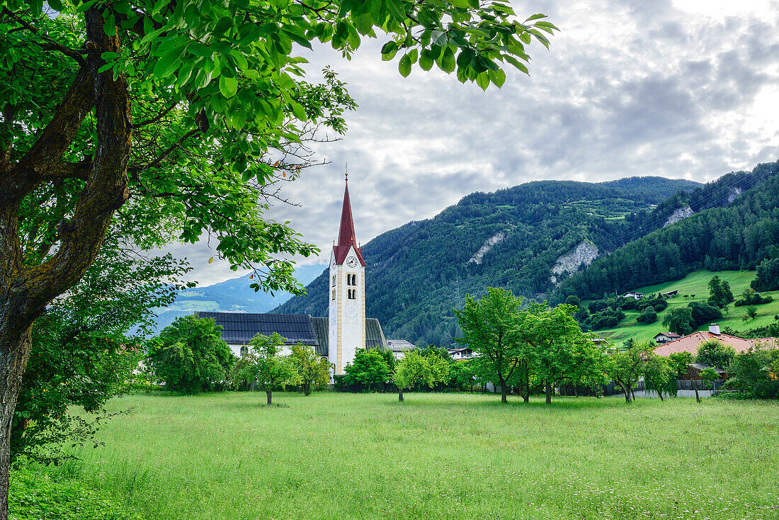 Blick über Streuobstwiese auf Pfarrkirche St. Leonhard, Ried im Oberinntal, Tirol, Österreich