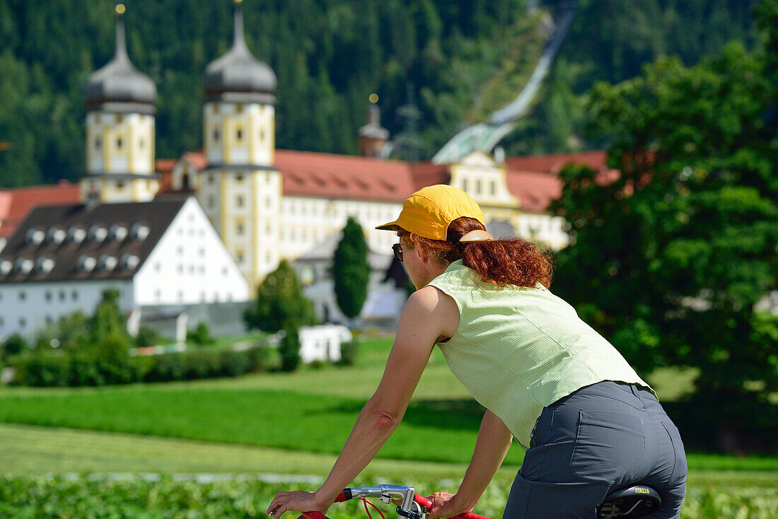 Woman cycling, monastery Stams in background, Stams, Tyrol, Austria