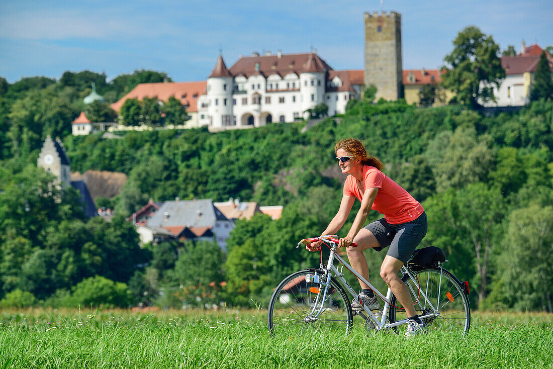 Frau fährt Fahrrad, Schloss Neubeuern im Hintergrund, Neubeuern, Oberbayern, Bayern, Deutschland