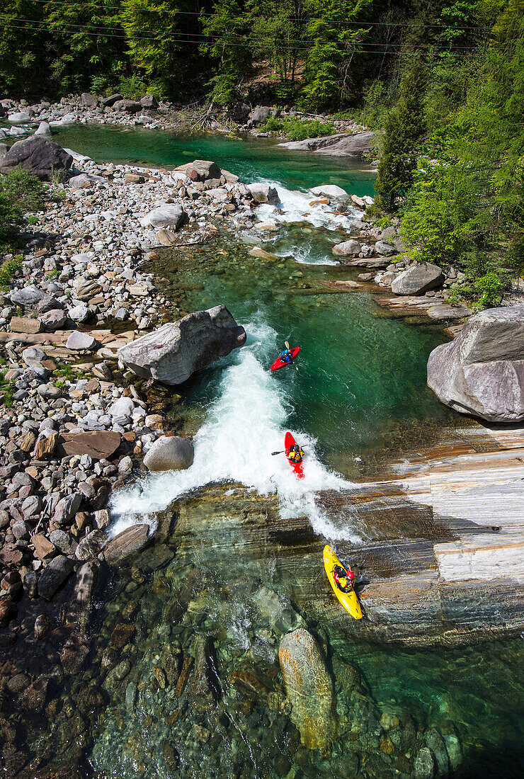 Three kayaker on the crystal clear waters of the Verzasca, Ticino, Switzerland