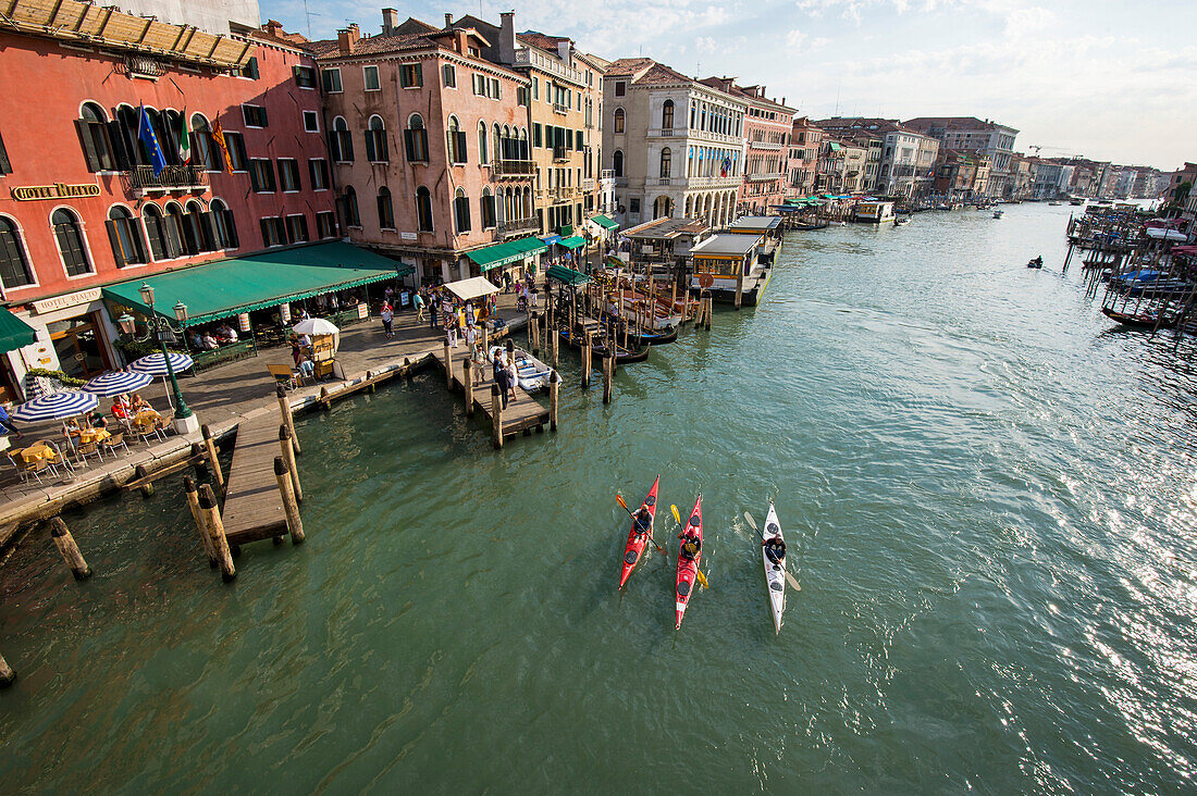 Three kayakers on the Canal Grande in front of the Rialto bridge, Venice, Italy