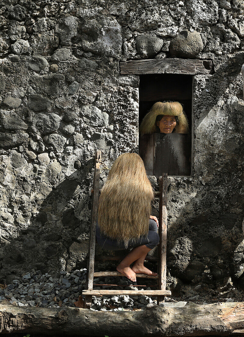 Ivatan Frau mit Perücke aus Stroh neben Steinhaus, Dorf, Sabtang Insel, Batanes, Philippinen, Asien