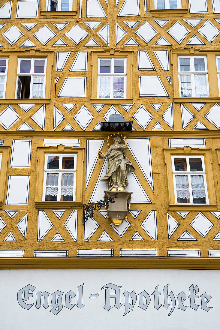 Half-timbered Engel Pharmacy building with religious figure in the old town, Ochsenfurt, Franconia, Bavaria, Germany