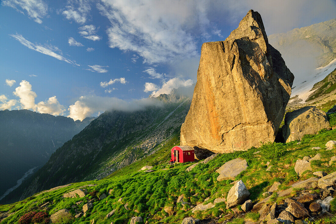 Red bivouac beneath boulder, Lombardy, Italy