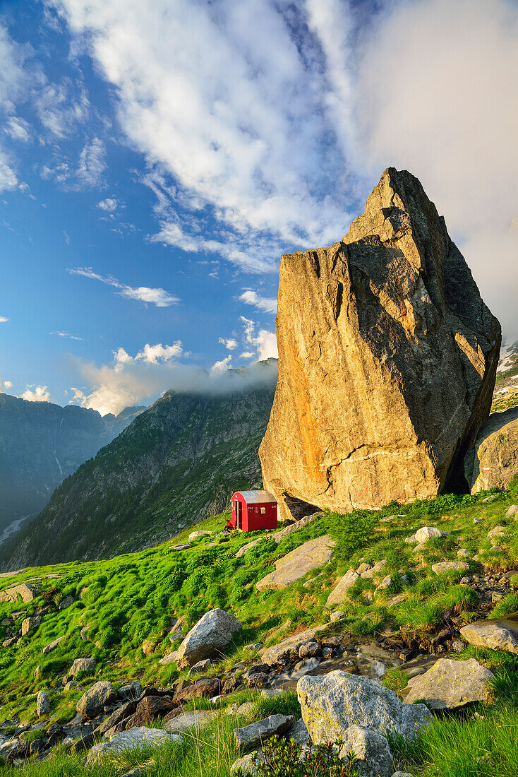 Red bivouac beneath boulder, Lombardy, Italy