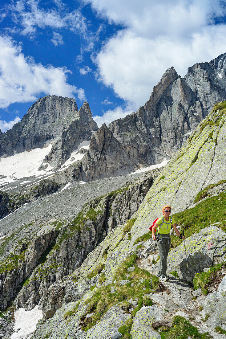 Woman hiking with Piz Badile in background, Sentiero Roma, Bergell range, Lombardy, Italy