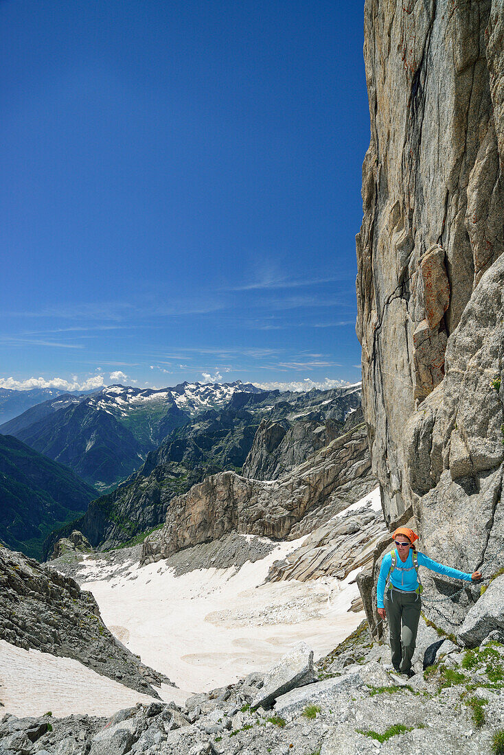 Frau steigt über versicherten Steig über Felsen auf, Sentiero Roma, Bergell, Lombardei, Italien