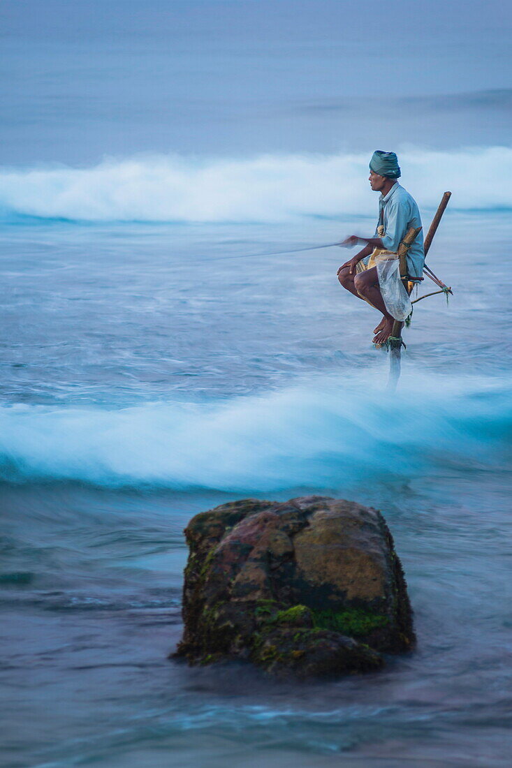 Stilt fishing, a stilt fisherman in the waves at Midigama near Weligama, South Coast, Sri Lanka, Indian Ocean, Asia