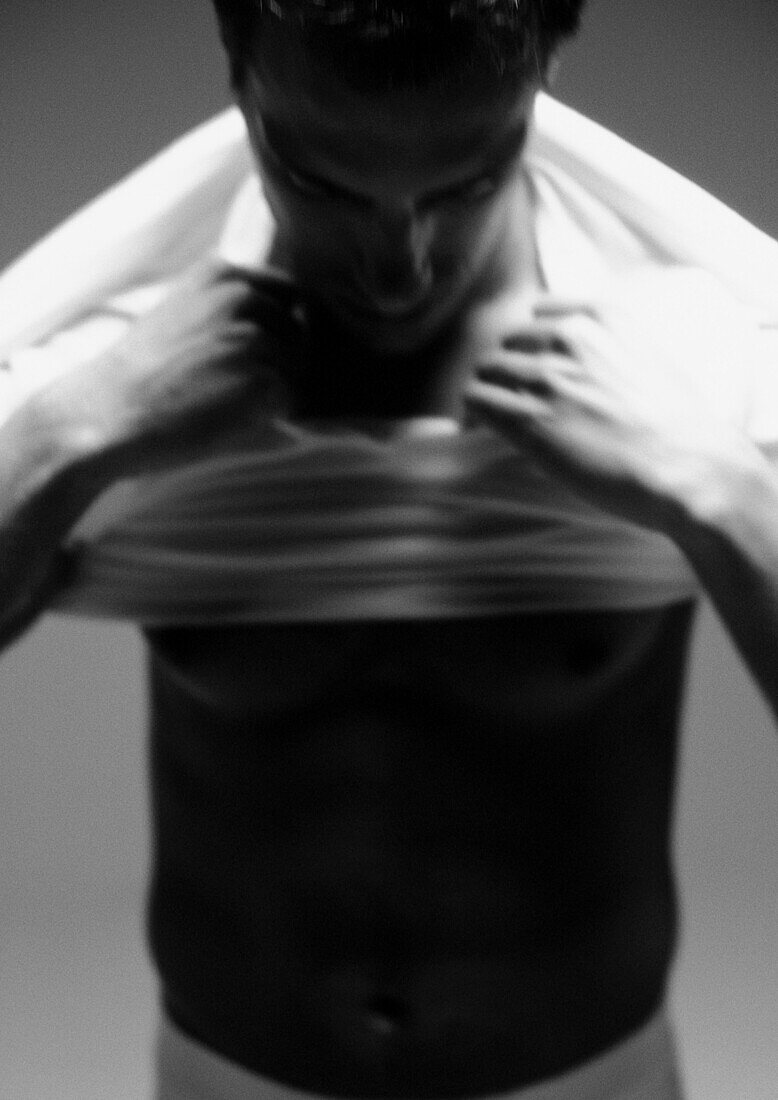 Man putting shirt on, blurred, close-up, black and white.