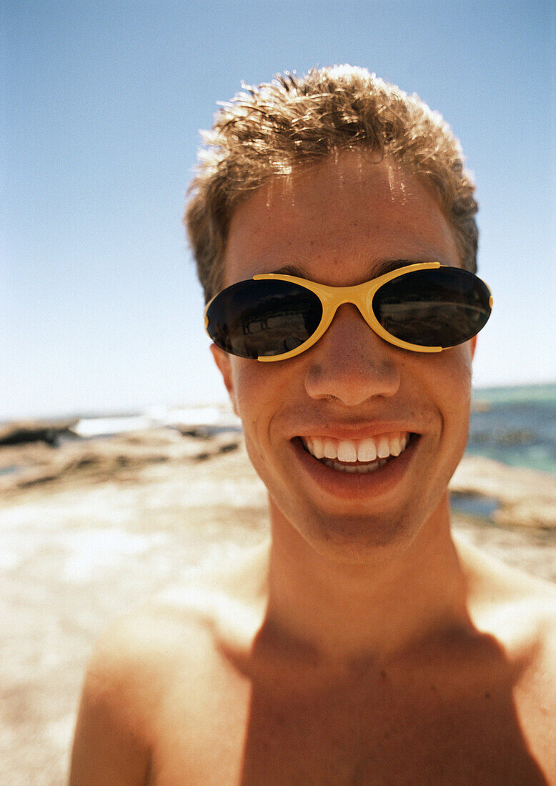 Close up of teenage boy  wearing sunglasses at the beach.