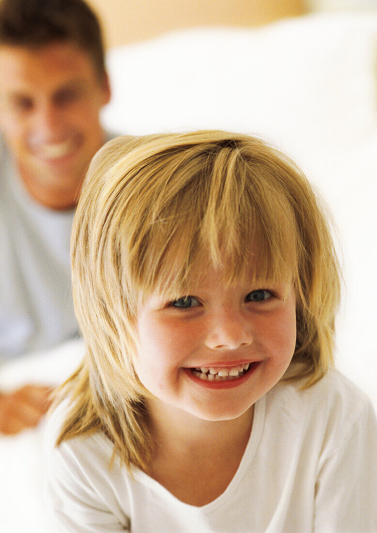 Little girl smiling at camera, father in background